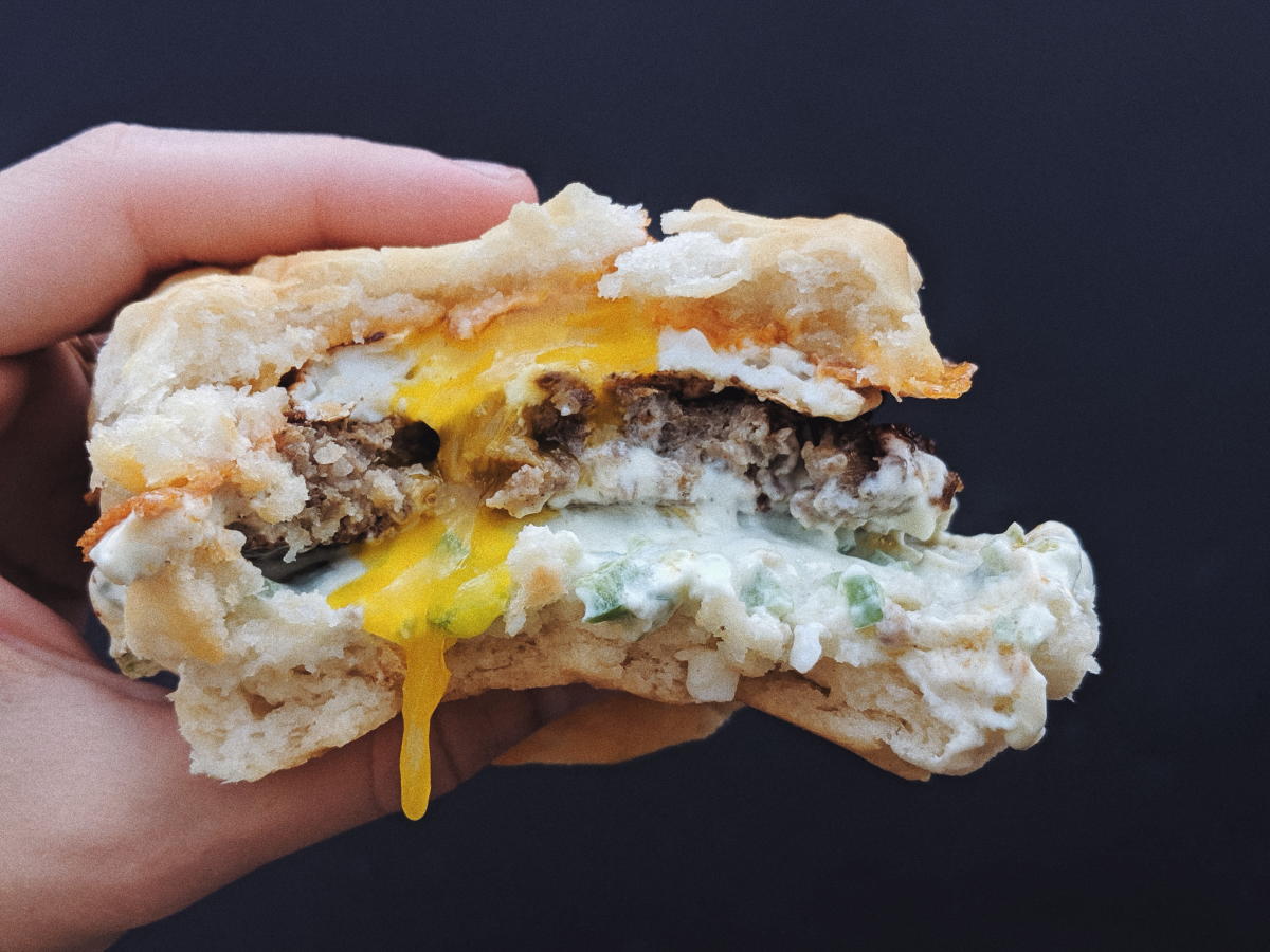 Someone holding a juicy, Cafe Racer sausage biscuit.